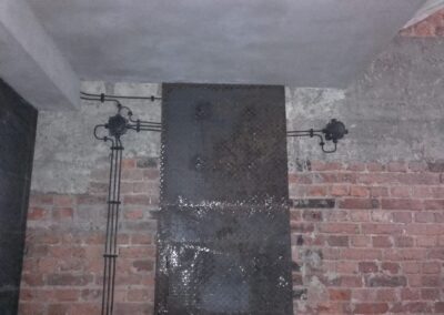 instalacja elektryczna natynkowa w piwnicy na cegle, czarne kable