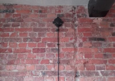 kabel zasilający położony natynkowo na cegłach